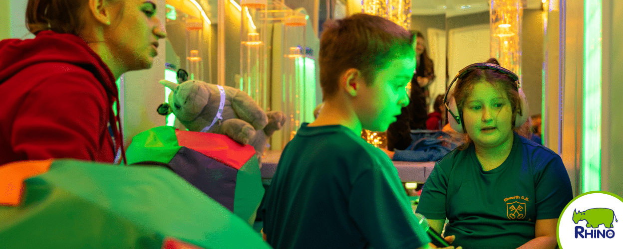 kids inside the rhino sensory trailer interacting with a sensory wall panel